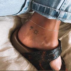 a woman's foot with a small tattoo on her left ankle and palm tree in the background