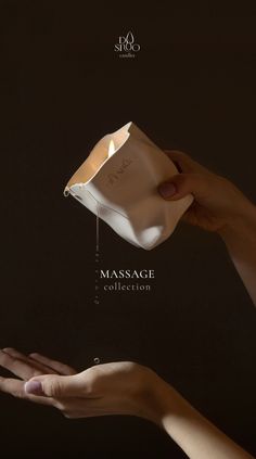 two hands holding an object with the words massage written on it, in front of a black background