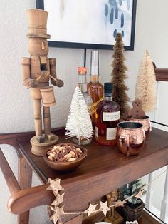 a wooden table topped with lots of bottles and christmas decorations next to a small tree