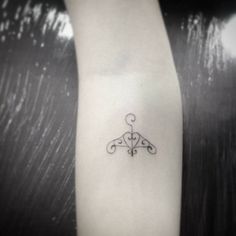 a black and white photo of a small tattoo on the left arm, with an ornamental design