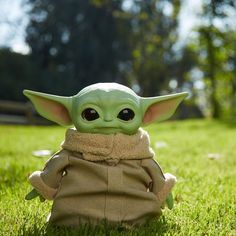 a baby yoda doll sitting in the grass