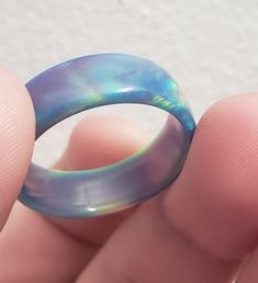 OPAREX synthetic opal is more durable and cost effective than your average opal, ensuring you will have your ring for years to come! The color shifts depending on the angle it is viewed, creating a rainbow of colors. The material is semi transparent, giving it an almost glowing effect. It is inspired by Dragon's Fire, displaying all the colors of a flame at it's hottest point. 8 mm wide This synthetic opal ring comes in a size 8 1/2 and was turned on a lathe. It is then sanded from 60 grit all t Blue Opal Round Ring, Blue Round Opal Ring, Iridescent Opal Ring With Unique Style, Unique Iridescent Round Opal Ring, Adjustable Blue Opal Ring, Multicolor Opal Round Ring, Handmade Iridescent Opal Ring, Handmade Blue Opal Rings, Multicolor Opal Ring