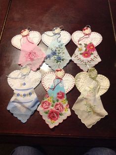 several pieces of cloth with flowers and hearts on them sitting on a wooden table next to a person's feet