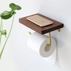 a cell phone is sitting on top of a toilet paper holder next to a plant