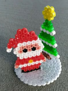 a lego santa clause is standing next to a small christmas tree on the ground,