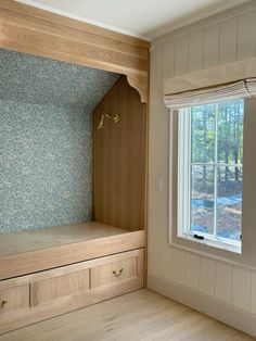 an empty room with some drawers and a bench in the corner, next to a window