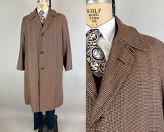 This 1950's overcoat is sure to give you a warm welcome to fall colors and cooler temps! The lovely wool combines vertical stripes of black and white, diagonal stripes of burnt sienna, and a windowpane plaid of pumpkin orange for a truly unique cloth. Classic style with raglan sleeves, buttoning cuff straps, four button closure with additional top loop, and welted pockets at the hip. Partial lining with a single inner pocket and straps for that over the shoulders look. All leather buttons. By "Swift" of San Francisco. This coat is in great vintage condition with no holes, stains, nor odors to note. Measurements taken flat and doubled where appropriate: Chest: 52" Raglan Sleeve: 35.5" measured nape to cuff Overall Length: 49" Find our other extra large vintage dapper deco duds here: https:/ Vintage Brown Double-breasted Pea Coat, Vintage Double-breasted Wool Coat, Vintage Brown Retro Single-breasted Outerwear, Vintage Wool Houndstooth Outerwear, Plaid Double-breasted Outerwear With Button Fastening, Plaid Wool Coat, Windowpane Plaid, Burnt Sienna, Diagonal Stripes