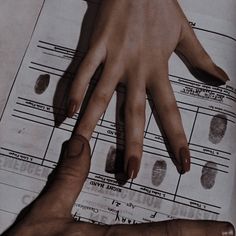 two hands touching each other on top of a sheet of paper with fingerprints