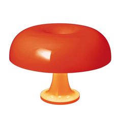 an orange table lamp sitting on top of a white surface