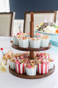 cupcakes are arranged on three tiered trays with candy and candies