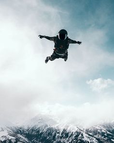 a man flying through the air while riding a snowboard in front of some mountains