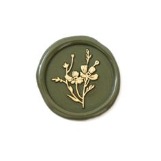 a green and gold button with flowers on it