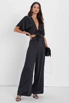 Your OOTN just got a hot, dynamic upgrade with the Lulus Flirt For Fun Black Tie-Front Two-Piece Wide-Leg Jumpsuit! This flirty two-piece jumpsuit has a sleek satin construction that shapes short sleeves, a cropped bodice, and a plunging V-neckline. The high waist has twin sashes that create a tie-front detail by tying through the top, lending trendy side cutouts to the 'fit. Relaxed, wide-leg pants fall to ankle-length hems. Hidden back zipper/clasp.