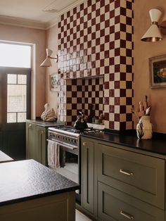 a kitchen with green cabinets and checkered backsplash on the wall above the stove