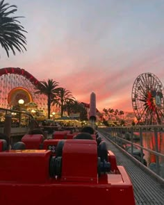 an amusement park at sunset with ferris wheel and palm trees