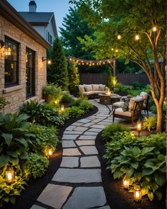 a stone path leads to a patio with lights on the trees and bushes around it