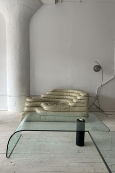 a glass coffee table sitting on top of a white tiled floor next to a couch