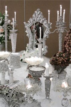 a table topped with lots of silver dishes and candles