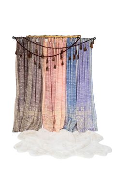 three different colored curtains hanging from a string on a white wall with fur rugs underneath them