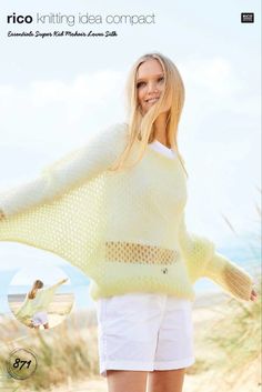 a woman standing on top of a sandy beach wearing a yellow sweater and white shorts