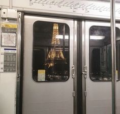 the eiffel tower is reflected in the doors of a subway car that has it's windows open