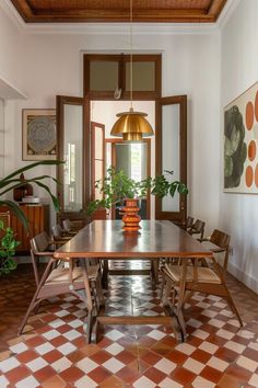 a dining room table with chairs and potted plants