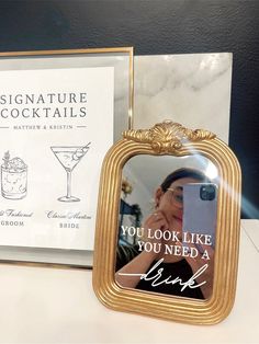 there is a gold frame with a picture on it next to a sign that says, you look like you need a drink