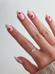 a woman's hand with pink nail polish and red heart shaped nails on it