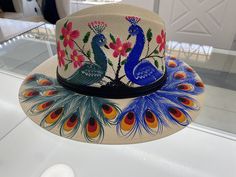 It's finally back!  Individually hand painted artisanal fedora hats. Each hat is meticulously hand painted by an artist. Each hat is unique and full of colors. Made by artists from Mexico the hats represent the beauty of Mexico.  Available this hat is light beige with Two Vibrant Peacocks and flower design. Vibrant colors with purple, red, teal, yellow, light blue and blue, fusia, and more! This hat is great for vacation in Tulum, Burning Man, Coachella, Beaches, or just brunching locally!  Made out of light canvas with air holes on top of hat for breathable and cool comfort. Size: Large has elastic band on inside and can fit most heads Inner is 8" Length and 7"" Width Hat is apprx 14" Length and 13" Width Does not include purse. Please note model is wearing a different design of fedora ha Handmade Multicolor Fedora With Curved Brim, Multicolor Hand Painted Hat With Curved Brim, Handmade Multicolor Flat Brim Fedora, Handmade Artistic Fedora With Curved Brim, Artisan Hand Painted Fedora For Kentucky Derby, Artisan Hand-painted Fedora For Kentucky Derby, Artsy Multicolor Fedora Hat, Handmade Adjustable Artistic Fedora, Artistic Handmade Wide Brim Fedora