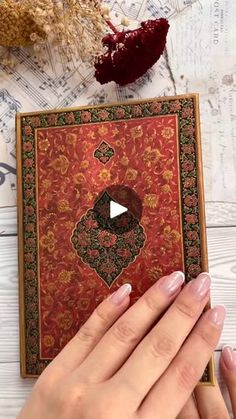 a woman's hands holding an ornate book with music notes on the table in the background