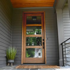 the front door of a house with a potted plant on the step and glass window