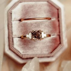 an engagement ring in a box on top of a cloth covered table with white flowers