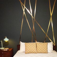 a bed with two pillows on top of it next to a night stand and lamp