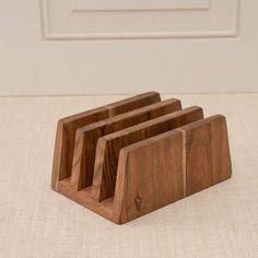 three wooden business card holders sitting on top of a white carpeted floor with a door in the background