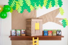 there is a cardboard tree and some books on the shelf in front of the wall