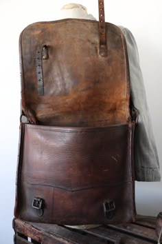 an old brown leather bag sitting on top of a wooden crate