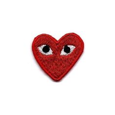 a red heart with two eyes on the side and one eye in the middle, embroidered onto it