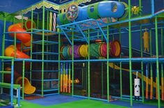 an indoor play area with lots of colorful toys and accessories on the walls, along with climbing ropes