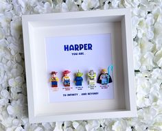 a white frame with four legos in it and the words harper you are surrounded by flowers