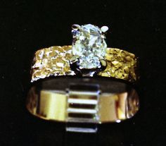 a yellow and white diamond ring sitting on top of a black surface