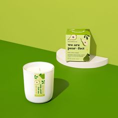 a white candle sitting on top of a green table next to a box of tea