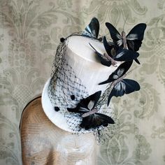 This elegant yet playful mini top hat is covered with ivory soie sauvage silk. It is decorated with black birdcage dotted veil, which is lushly placed all around the crown along with beautiful black and beige butterflies, which are playfully placed all around the hat for a 3D visual effect.  This mini hat can also be made in white along with black decoration. This mini top hat is fully lined with satin and attaches to the head with thin elastic that goes under the hair, to ensure stability and achieve that perfect angled look.  Measurements : approx.4  inches (10 cm) tall , 6.5 inches (16.5 cm) front to back and 5.5 inches (14 cm)side to side This item is sent packaged securely and sent out with DHL Express, delivered in 2-6 days depending on your location. Please, add your phone number at Black Novelty Mini Hats For Themed Events, Black Adjustable Mini Hats In Fantasy Style, Novelty Black Top Hat For Costume, Black Gothic Mini Hat Adjustable, Black Victorian Mini Hat, Top Hat Costume, Alice In Wonderland Hat, Bridal Fascinator, Butterfly Top