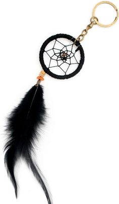 a black feather keychain with an orange bead on the end and a white background