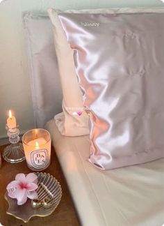 two candles are sitting on a table next to a pillow and some other things in front of it