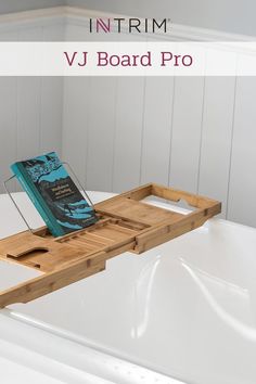 a bath tub with a wooden tray holding a book on top of it and the words intrim vj board pro above it