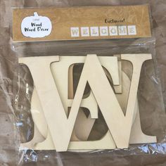 a package of wooden letters sitting on top of a plastic bag with the word welcome written in it