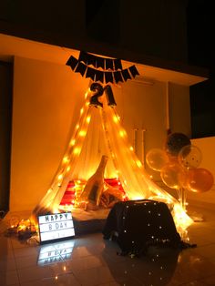 a birthday decoration with balloons and lights on the floor in front of a teepee tent