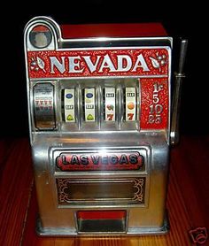 a silver and red vending machine sitting on top of a wooden table