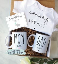 two coffee mugs in a gift box with the words congratulations son and mom written on them