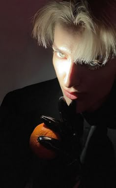 a man with blond hair holding an orange